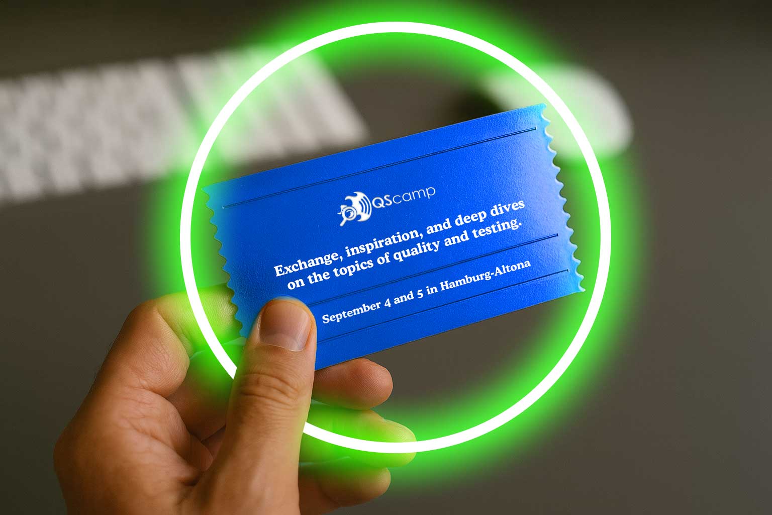 One hand is holding a blue ticket with the Barcamp logo and slogan on it.